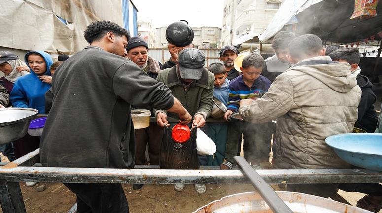مواطنون نازحون يتلقون وجبات طعام ساخنة من تكية خيرية  في مخيم النصيرات وسط قطاع غزة