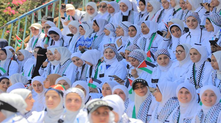 طلبة من كلية التمريض وعلوم الصحة في الكلية الجامعية للعلوم التطبيقية يشاركون في فعالية "ارتداء المعطف الأبيض وأداء القسم التمريضي" بين أنقاض مباني الكلية المدمرة في مدينة غزة