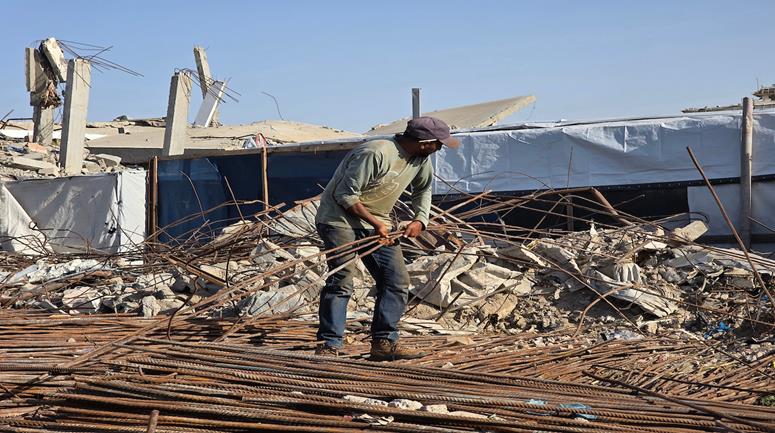 مواطنون يستخرجون حديد البناء من المباني التي دمرها الاحتلال لإعادة تدويره واستخدامه في بناء الخيام والملاجئ المؤقتة