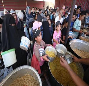 نازحون يتجمعون للحصول على الطعام المجاني من إحدى التكيات الخيرية في مخيم النصيرات وسط قطاع غزة