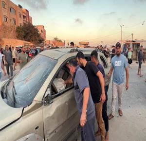 مواطنون يتفقدون مركبة مدمرة في منطقة الزوايدة وسط قطاع غزة، عقب غارة نفذتها طائرات الاحتلال الاسرائيلي