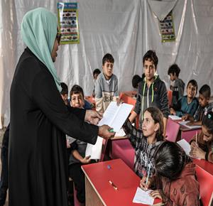 أطفال نازحون يحضرون درسًا داخل خيمة تُستخدم كصفّ مؤقت في أحد مراكز الإيواء بدير البلح وسط قطاع غزة