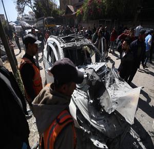 مواطنون يتفقدون مركبة بعد استهدافها بصاروخ إسرائيلي غرب مدينة غزة، ما أدى إلى استشهاد أربعة وإصابة آخرين