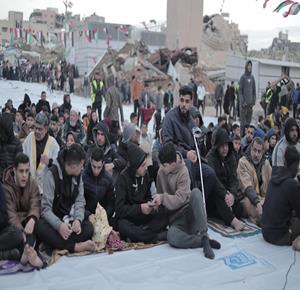 مواطنون يؤدون  صلاة عيد الفطر في العراء بجانب مسجد حمزة المدمر في مدينة غزة.